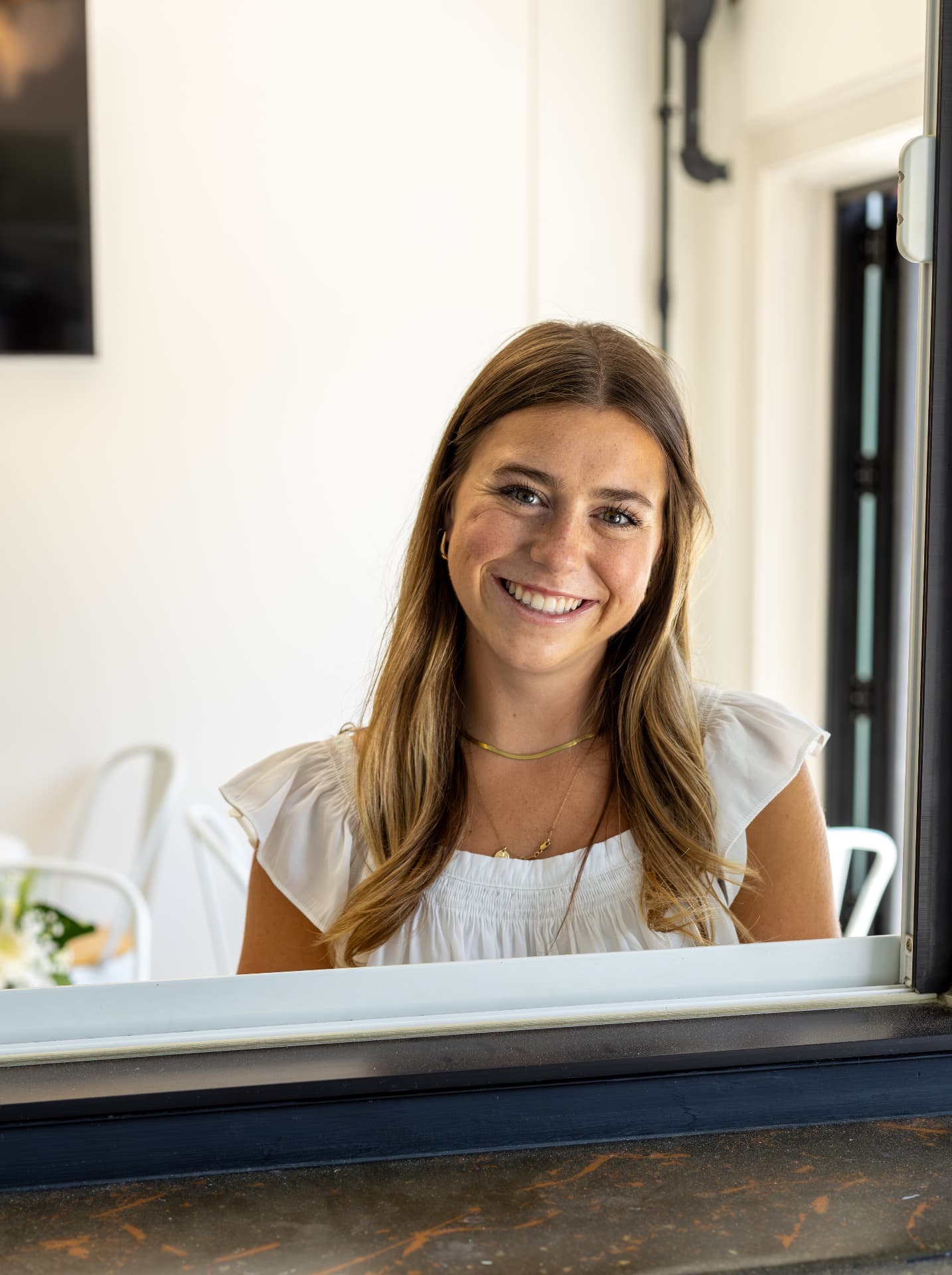 Allison standing behind the espresso machine at The Grounds with a cup in hand